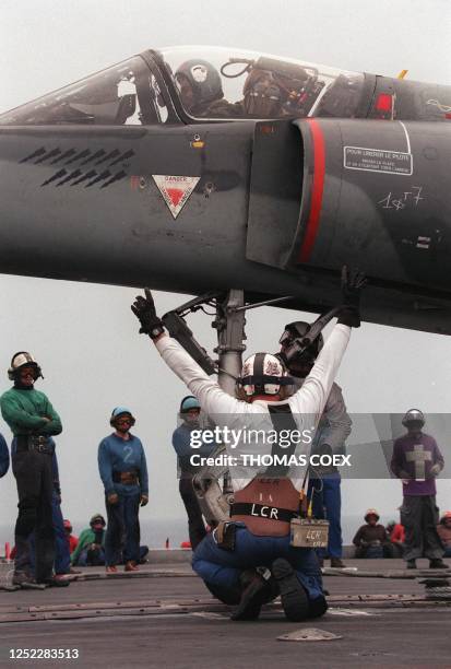 Les apponteurs assistent le pilote d'un Super-Etendard pour se positionner au décollage sur le porte-avions français, le 20 mai, en mer Adriatique,...