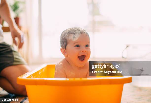 leuke baby die in een badkuip speelt - hot shower stockfoto's en -beelden