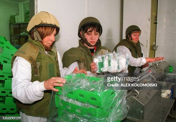 Workers at a dairy factory in Nahariya near the Lebanese border wear flak jackets and helmets as they pack cheese 09 February 2000. Israelis along...