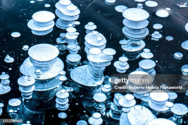 ice bubbles trapped under water surface - icicle stock pictures, royalty-free photos & images