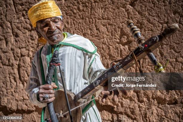 Man dressed in typical Berber costume playing a stringed instrument, known as Ribab, in the alleys of the Kasbah Taourirt.