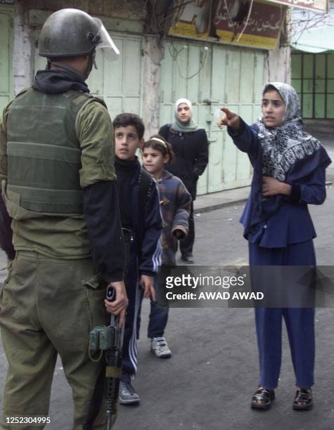 Young Palestinian woman argues with an Israeli soldier as she attempts to enter an area that has been closed off by the Israeli army in the West Bank...
