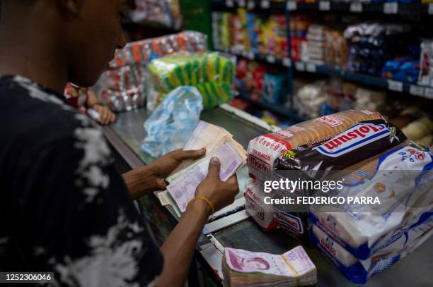 Man counts Bolivar bills to buy groceries in a supermarket in Caracas, on April 28, 2023.