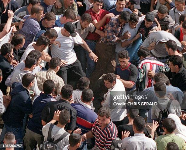 Palestinians lynch at an undercover Israeli soldier in the West bank town of Ramallah 12 October 2000. Two Israeli soldiers were killed by a furious...