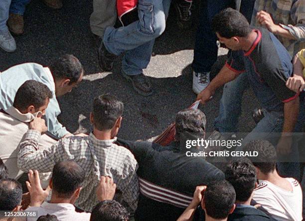 Palestinian pulls the blood-soaked T-shirt of an undercover Israeli soldier in the West bank town of Ramallah 12 October 2000. Israeli missiles hit...