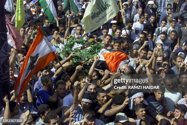 Palestinian mourners carry the body of Hassan Hassanein during his funeral in Beirut 08 October 2000. Hassanein was shot dead the previous day when...