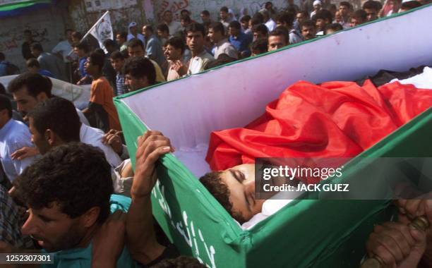 Palestinians carry the coffin of 18-year-old Karam Omar Ganan in the streets of Khan Yunes in the Gaza Strip during his funeral 12 October 2000....