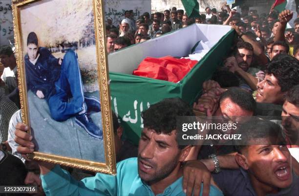 Palestinians, holding a picture of 18-year-old Karam Omar Ganan, march with his coffin in the streets of Khan Yunes in the Gaza Strip during his...