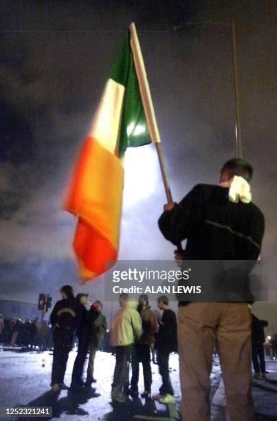 Masked youth waves an Irish flag in the eerie darkness lit up by the searchlight from an army helicopter hovering overhead in the Ardoyne area of...