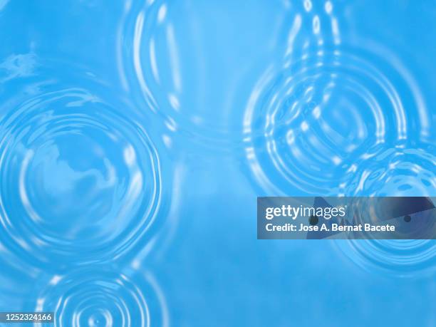 rainwater drops on a blue background. - water puddle stock pictures, royalty-free photos & images