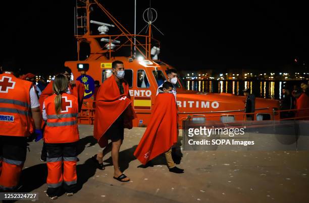 Migrant boy wearing a face mask is seen walking toward a humanitarian emergency stall after he arrives at Port of Malaga. Salvamento Maritimo rescued...