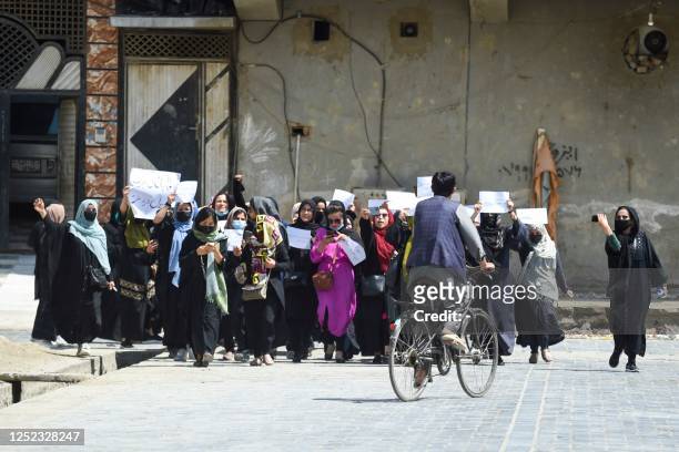 Afghan women hold placards as they march to protest for their rights, in Kabul on April 29, 2023. - Afghan women protested in Kabul on April 29,...