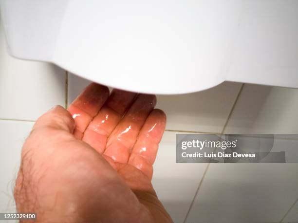 man drying hands - modern dryer with blue light - hand dryer stock pictures, royalty-free photos & images