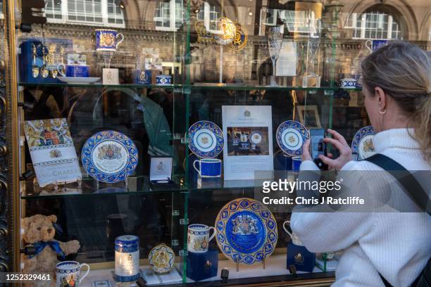 Tourist takes photos of commemorative memorabilia for sale at the Buckingham Palace shop on April 29, 2023 in London, England. The Coronation of King...