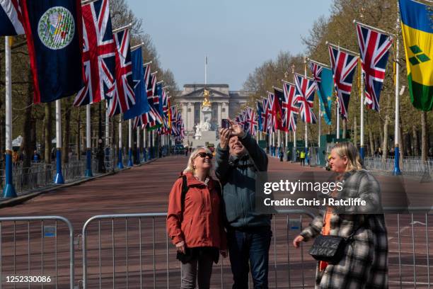 Tourists take photos on The Mall in front of Buckingham Palace on April 29, 2023 in London, England. The Coronation of King Charles III and The Queen...