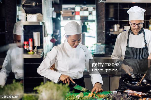 afroamerikanische frau koch in der restaurantküche mit ihrem küchenchef - kochlehrling stock-fotos und bilder