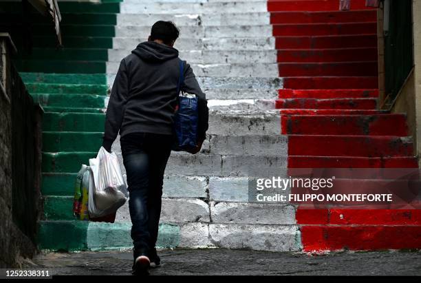Pedestrian walks on coloured stairs with Italian flag in the Quartieri Spagnoli in central Naples on April 29 on the eve of the Italian Serie A...
