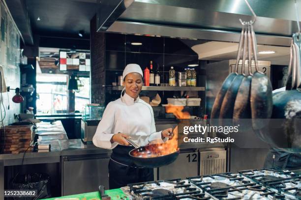 de vrouwelijke chef-kok bereidt een flambé specialiteit voor - black cook stockfoto's en -beelden