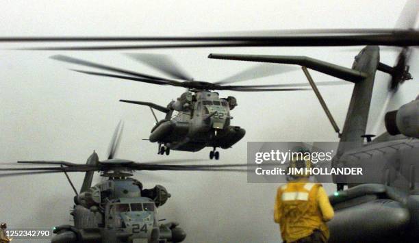 Marine CH-53 helicopters lifts off as two others ready for lift off from the deck of the amphibious assault ship USS Peleliu 25 November 2001 as...