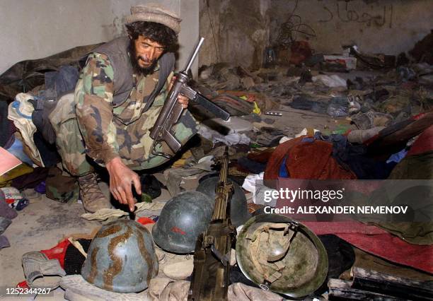 Northern Alliance soldier inspects helmets, machineguns and other belongings left by members of 'Al Ansar' terrorist group in their former base in...