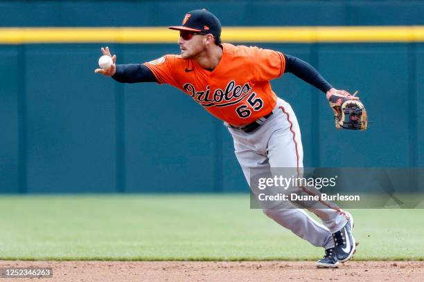 Second baseman Joey Ortiz of the Baltimore Orioles flips the ball hit by Javier Baez of the Detroit Tigers to second base to start a double play...