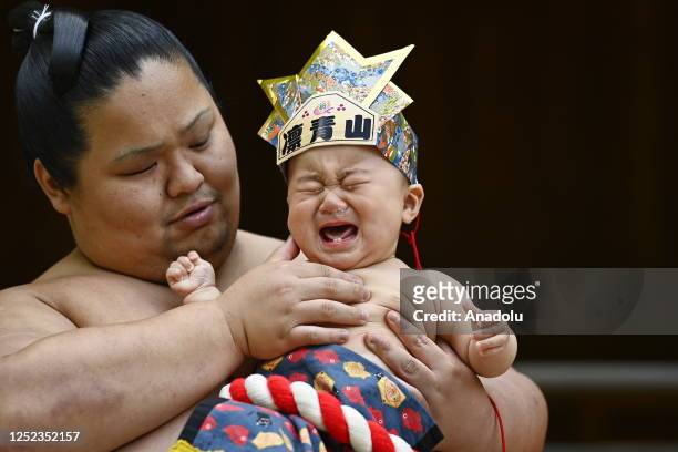 Baby cries as he is carried by a sumo wrestler on a ring during the Nakizumou event at Sanctuary Yukigaya Hachiman on April 29 in Tokyo, Japan....