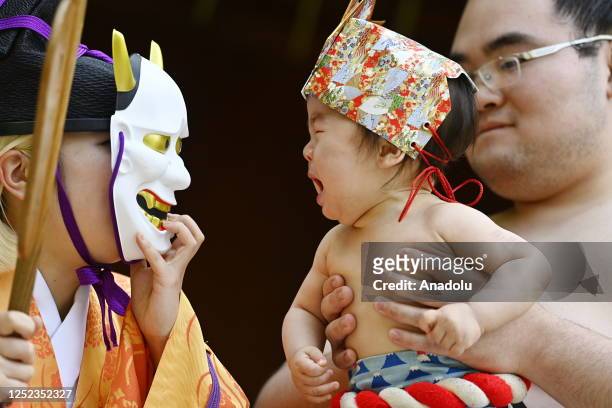 Person wearing a evil mask tries to make a baby cry who is carried by sumo wrestler on a ring during the Nakizumou event at Sanctuary Yukigaya...