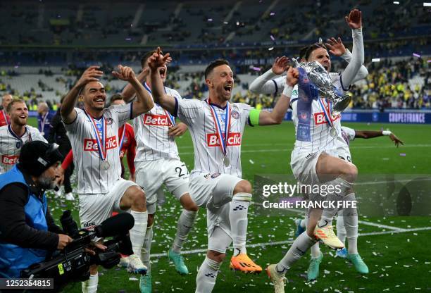 Toulouse's Belgian midfielder Brecht Dejaegere holds the trophy with his teamates after winning the French Cup final football match between Nantes...