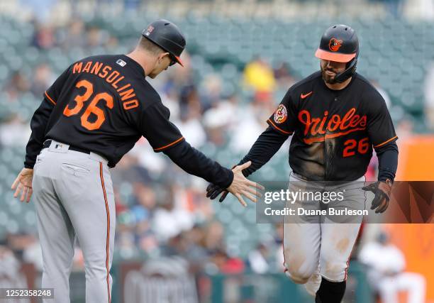 Ryan McKenna of the Baltimore Orioles is congratulated by third base coach Tony Mansolino after hitting a solo home run against the Detroit Tigers...