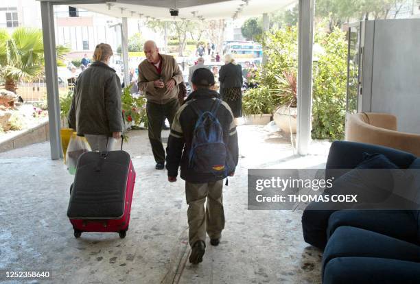 Tourist leaves with her son Netanya's Park Hotel 28 March 2002, following a suicide attack late last night that killed 20 people plus the Palestinian...