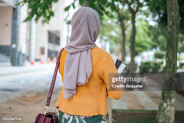 rückansicht von jungen asiatischen mädchen mit buch im freien - hijab woman from behind stock-fotos und bilder