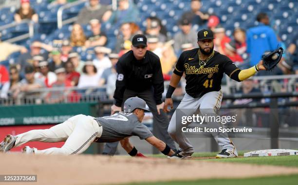 Pittsburgh Pirates first baseman Carlos Santana catches a pick off throw at first base while Nationals left fielder Alex Call dives back head first...