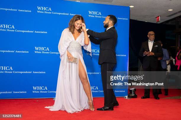 John Legend helps adjust Chrissy Teigen's dress on the red carpet of the White House Correspondents Dinner hosted at the Washington Hilton in...