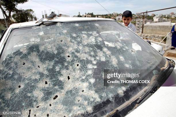 Ahmed, the son of Palestinian Agence France-Presse photographer Hossam Abu Alan stands near his father's bullet-ridden car 23 May 2002 in front of...