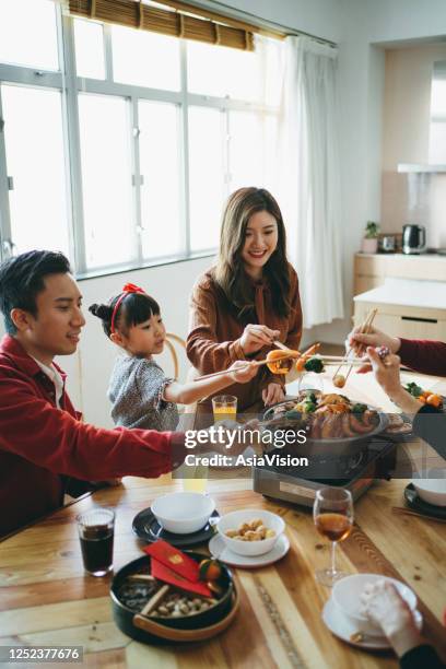 three generations of joyful asian family celebrating chinese new year and enjoying scrumptious traditional chinese poon choi on reunion dinner - chinese family dinner stock pictures, royalty-free photos & images