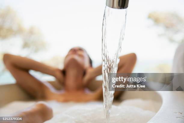 sensual woman enjoying bubble bath behind water faucet - alluring fitness stock pictures, royalty-free photos & images