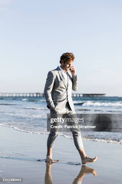 barefoot businessman walking on sunny ocean beach, los angeles, california - patrick walker stock pictures, royalty-free photos & images