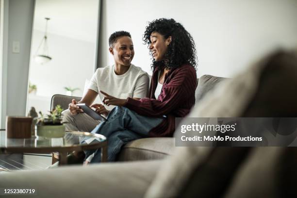 lesbian couple at home using digital tablet - tablet couple stock pictures, royalty-free photos & images