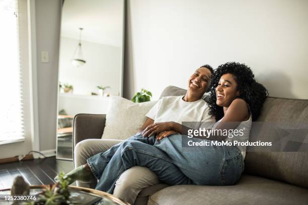 lesbian couple at home snuggling on couch - nosotroscollection stockfoto's en -beelden