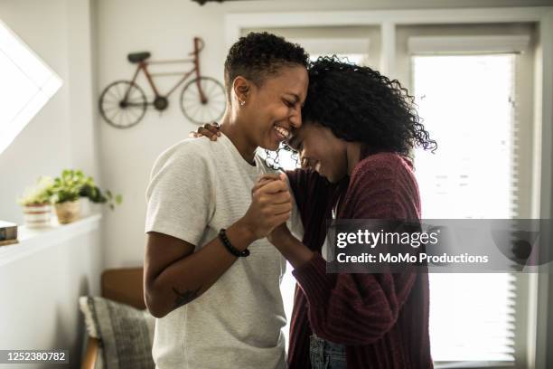 lesbian couple dancing in living room - gleichgeschlechtliches paar stock-fotos und bilder
