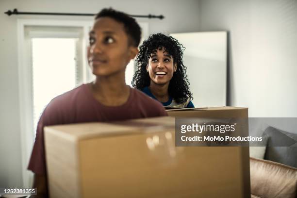 lesbian couple carrying moving boxes into home - körperliche aktivität stock-fotos und bilder