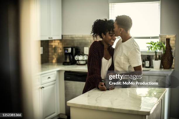 lesbian couple embracing in kitchen - black lesbians kiss stock pictures, royalty-free photos & images