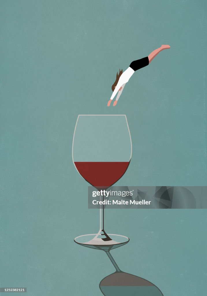 Businesswoman diving into large glass of wine