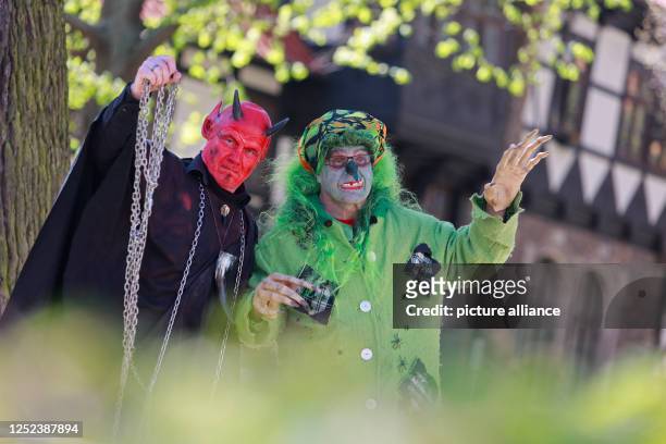 April 2023, Saxony-Anhalt, Wernigerode: In witch and devil costumes, two Walpurgis visitors in Wernigerode stand before storming the town hall in the...
