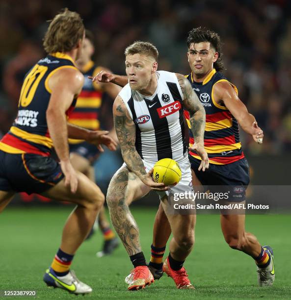 Jordan De Goey of the Magpies handpasses the ball while Josh Rachele of the Crows prepares to tackle during the 2023 AFL Round 07 match between the...