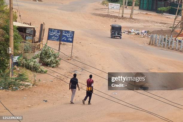 People walk on a deserted street in Khartoum on April 30 as clashes continue in war-torn Sudan. Heavy fighting again rocked Sudan's capital on April...