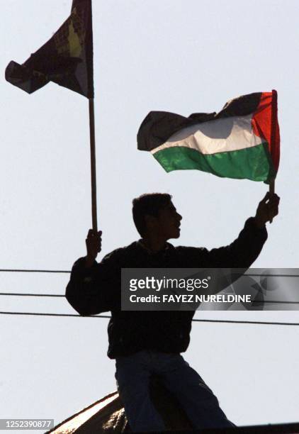 Palestinian protester holds up his national and the Islamic Jihad movement flags during a demonstration held by the movement in front of the...