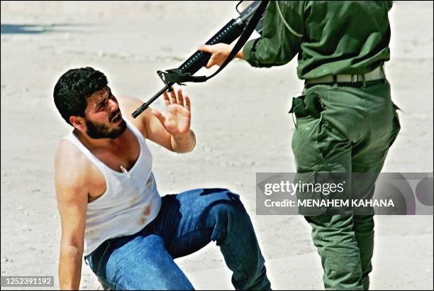 Israeli border policeman points his rifle on a Palestinian 08 October 1990 during the serious rioting at the Al-Aqsa mosque compound in Jerusalem's...