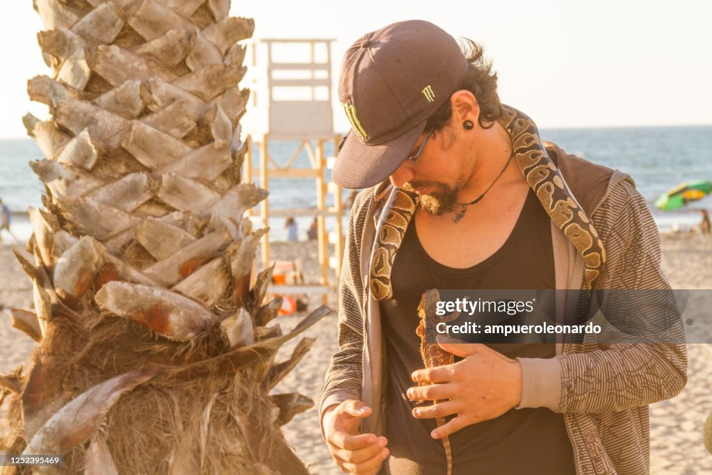 Man working with a snake and lizard for tips at the beach