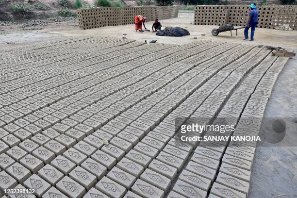 Labourers work at a brick factory on the outskirts of Prayagraj on April 30, 2023.